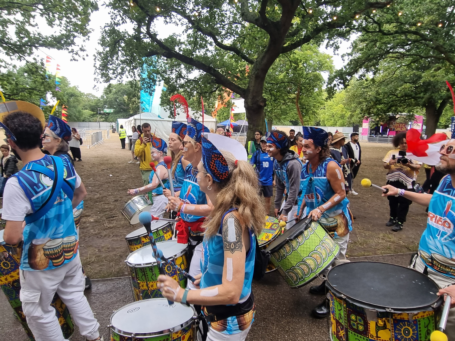 TRIBO drummers playing under festival bunting and Latin American flags in a London park