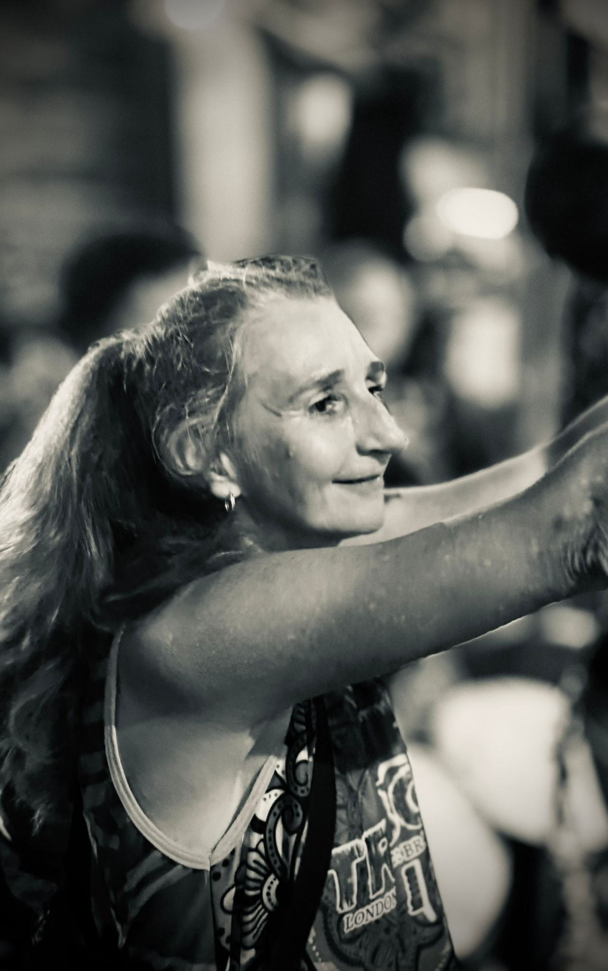 Profile of a TRIBO member playing a hand drum in the crowd during an evening rehearsal