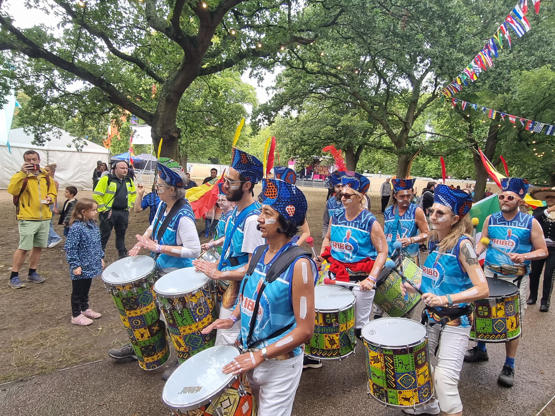 TRIBO drummers performing for a festival crowd in London with flags of Latin American countries flying