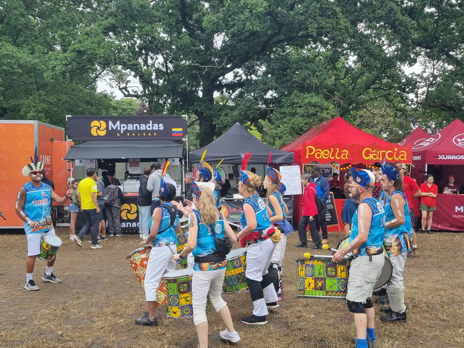 TRIBO bloco playing beside Latin American food stalls at an outdoor festival in London