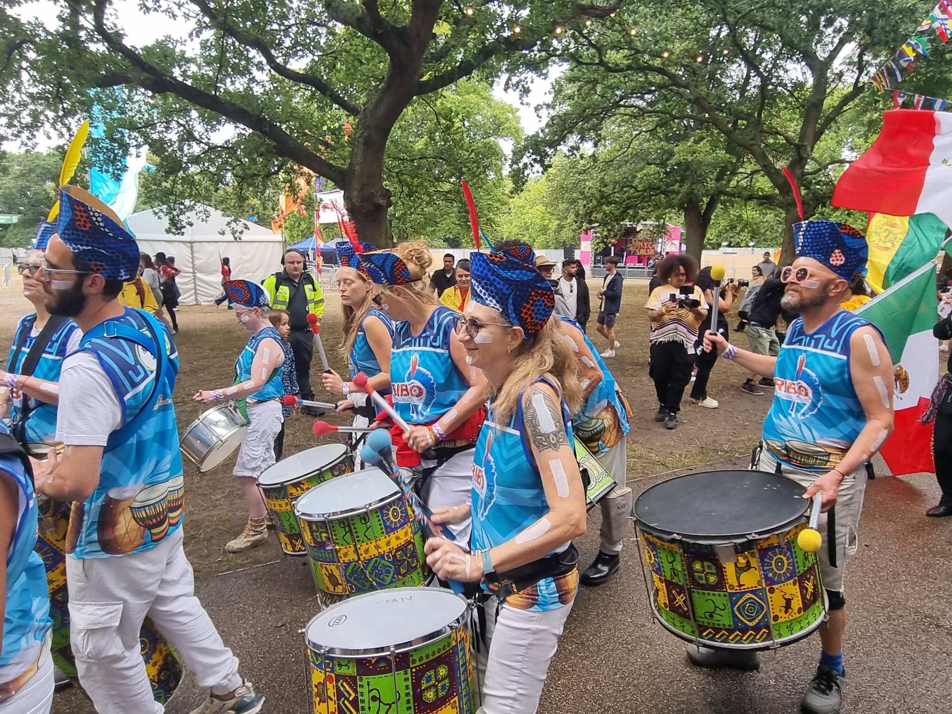 Close view of TRIBO surdo and conga players in blue vests during a London festival performance