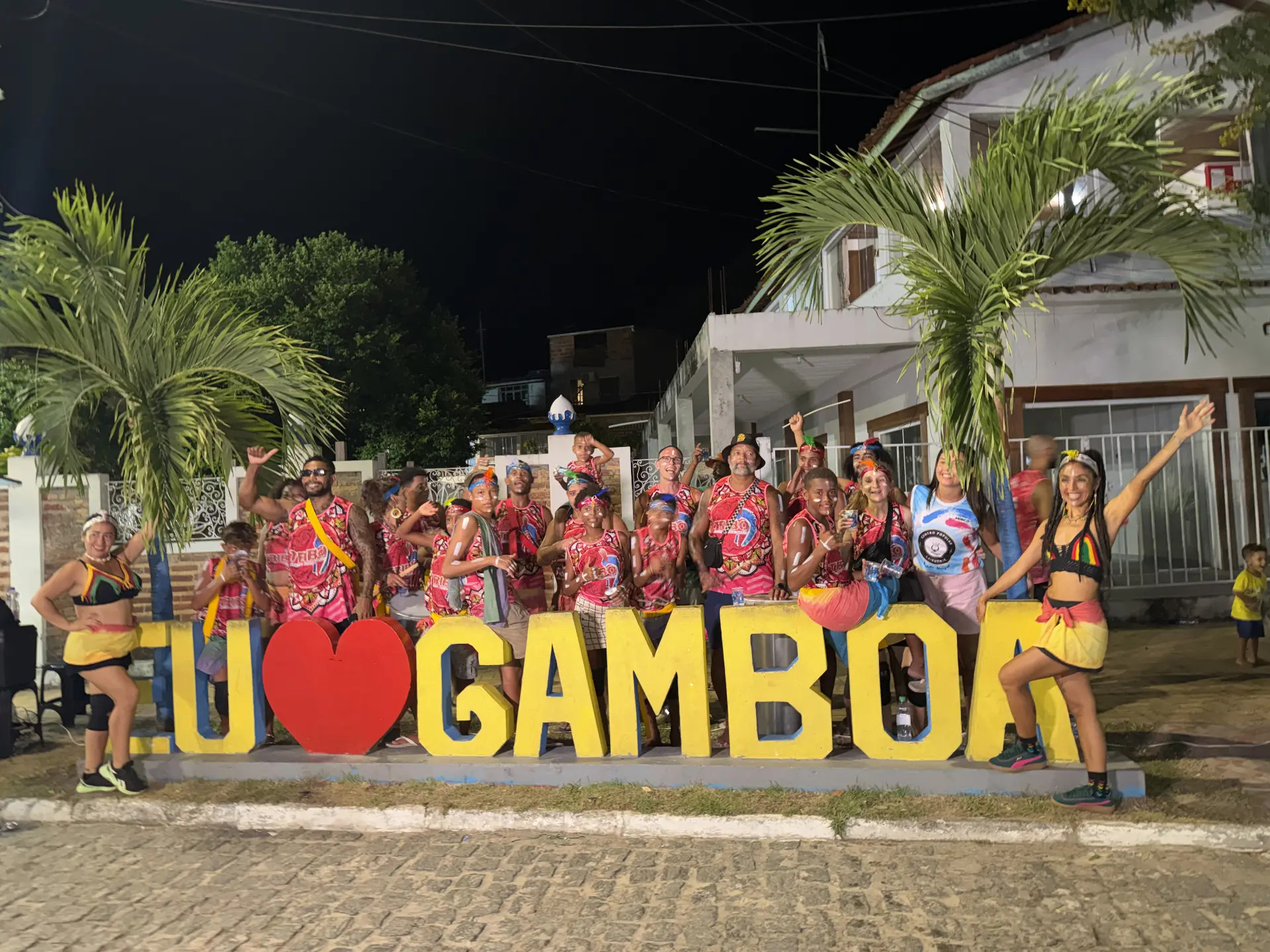 TRIBO members and dancers celebrating together at the Eu Amo Gamboa sign at night