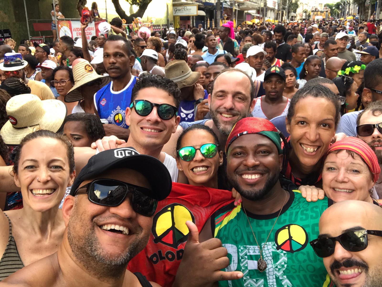 Group selfie of TRIBO members smiling in the middle of a packed carnival crowd in Salvador, Bahia