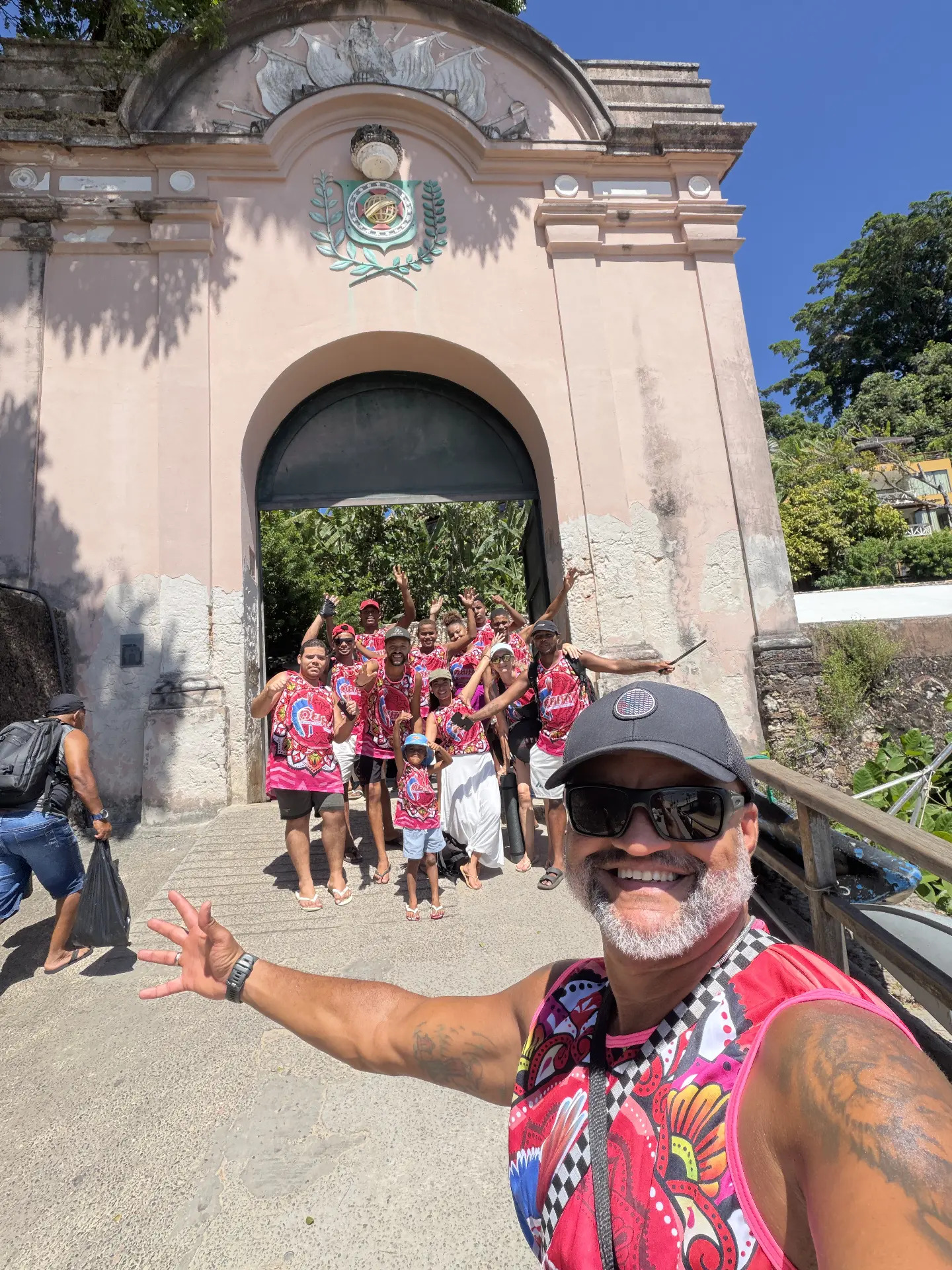 Large group of TRIBO members in band vests at the gate of a historic fort in Bahia, Brazil