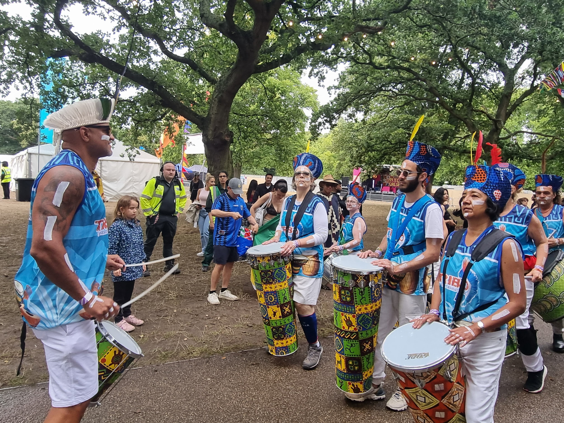 TRIBO director conducting the group with drumsticks while the drummers watch during a London performance